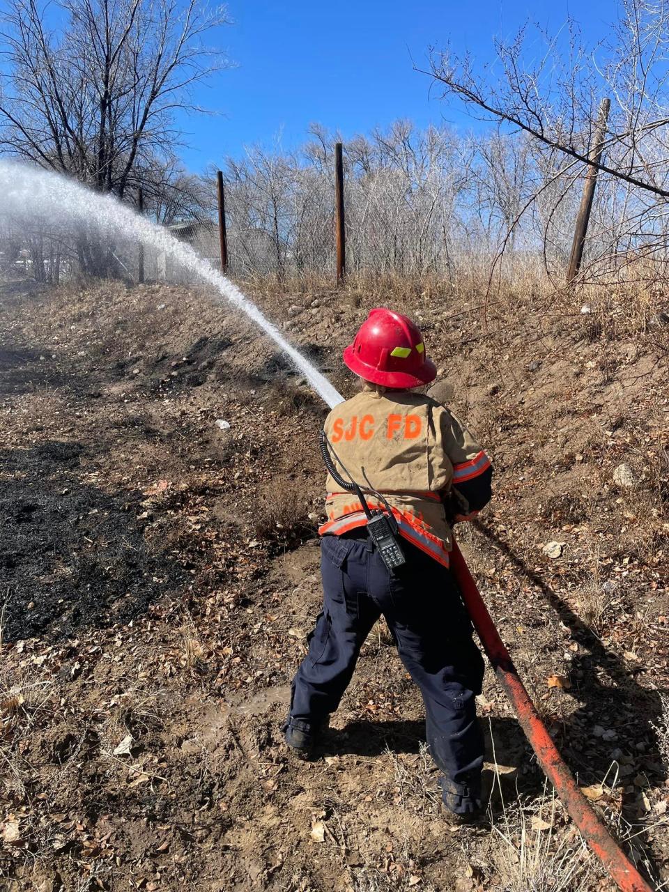 A San Juan County firefighter sprays water on a wildland blaze near County Road 3050 on Feb. 19.