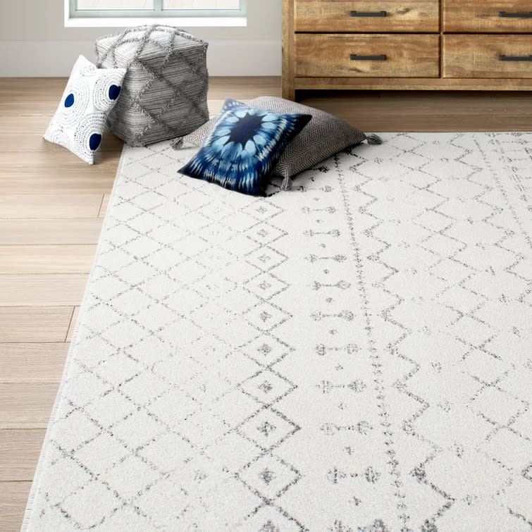 Giannini Geometric Area Rug in Grey/white on wooden floor