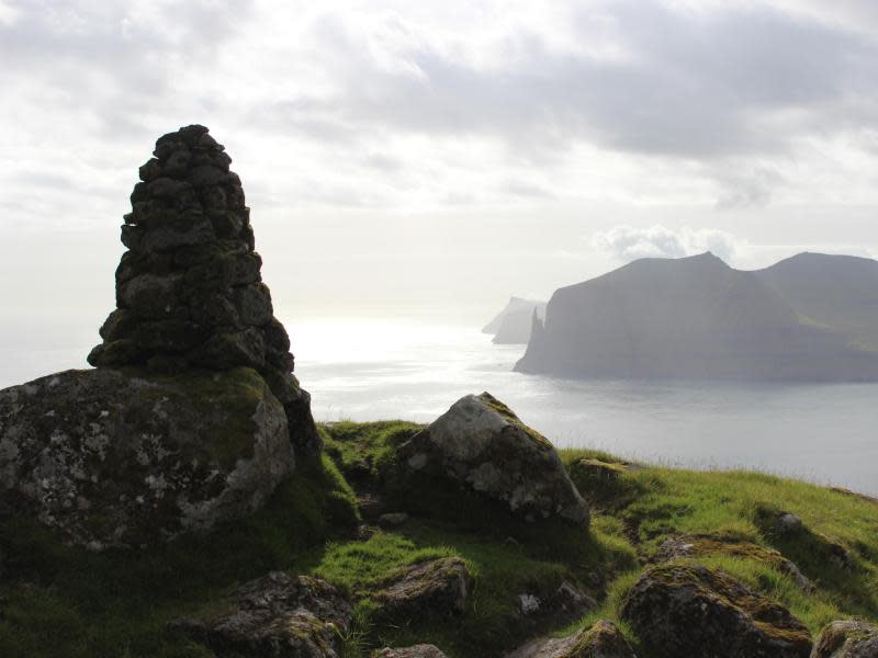 Auf den Färöer Inseln tauchen Fabelwesen überall in der Natur auf: Zum Beispiel beim Trøllkonufingur, dem Hexenfinger, einem Monolith an der Südküste von Vágar (hinten). Foto: Lea Sibbel