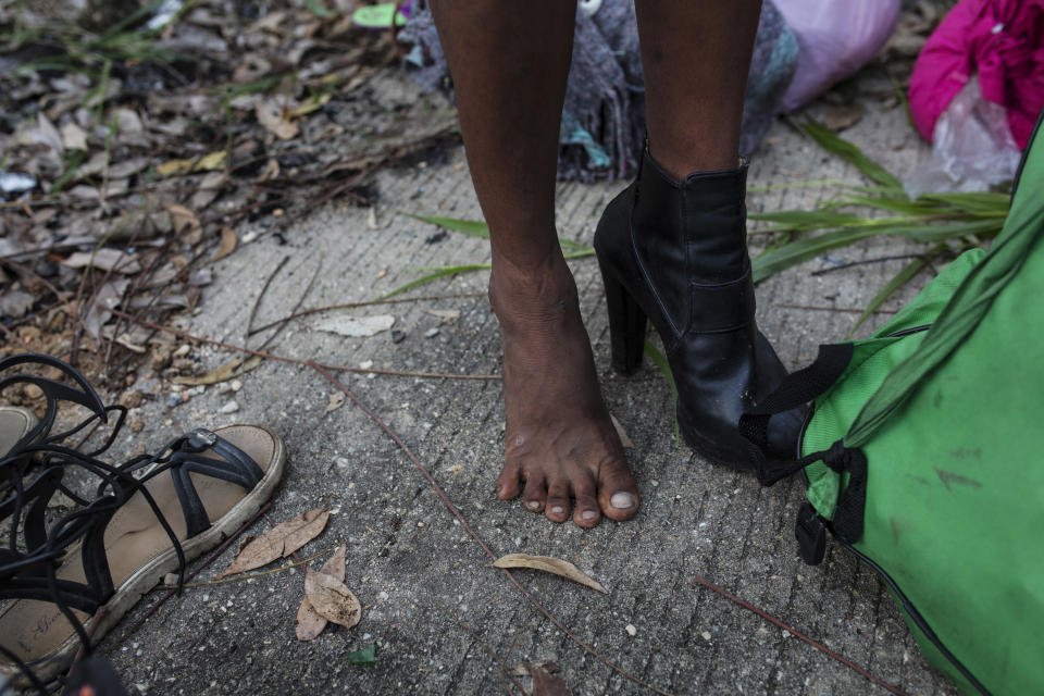 In this Nov. 3, 2018 photo, Honduran transgender Alexa Amaya, who is part of a group of 50 or so LGBTQ migrants traveling with the migrant caravan hoping to reach the U.S. border, tries on donated footwear at a shelter in Sayula, Mexico. Each night "the girls," as they call themselves, sift through piles of clothing donated by locals to try to look as sharp as possible. (AP Photo/Rodrigo Abd)