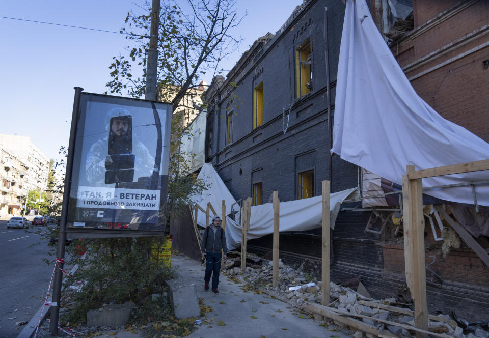 A man passes by a building damaged in a Russian rocket attack a week ago, in central Kyiv, Ukraine, Sunday, Oct. 16, 2022. (AP Photo/Efrem Lukatsky)