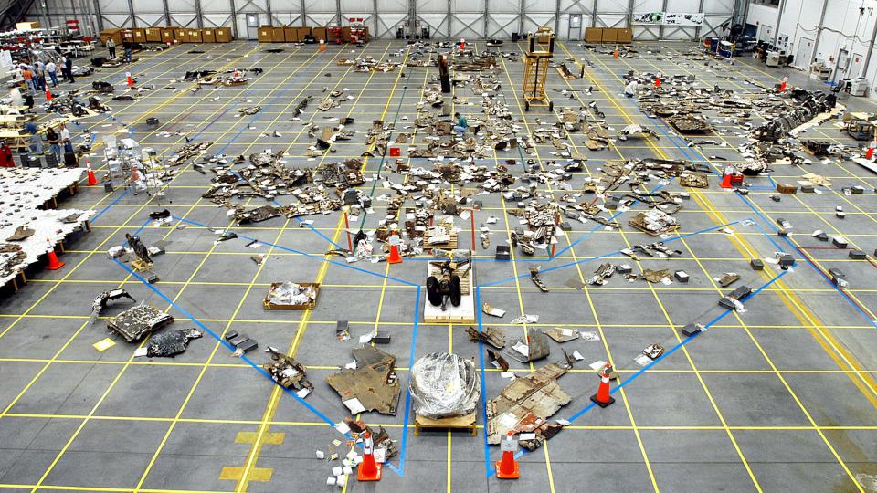 columbia debris lying on floor in hangar. an outline of the space shuttle marks the relative position of each piece of debris