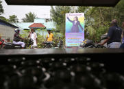 Indian villagers gather outside a local eatery next to a banner featuring U.S. Vice President-elect Kamala Harris with a message wishing her best, in Thulasendrapuram, the hometown of Harris' maternal grandfather, south of Chennai, Tamil Nadu state, India, Wednesday, Jan. 20, 2021. A tiny village in a remote part of South India is gearing up for celebrations ahead of Kamala Harris’ inauguration as the first female vice president of the United States. (AP Photo/Aijaz Rahi)