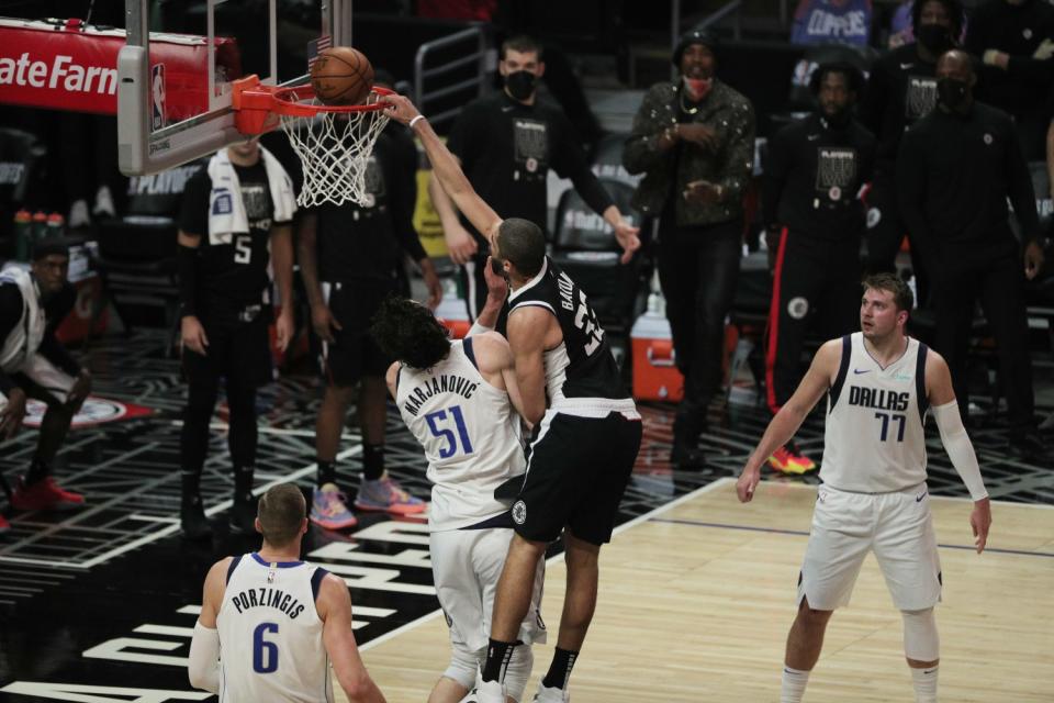 Clippers forward Nicolas Batum is fouled by Mavericks center Boban Marjanovic on a dunk attempt.