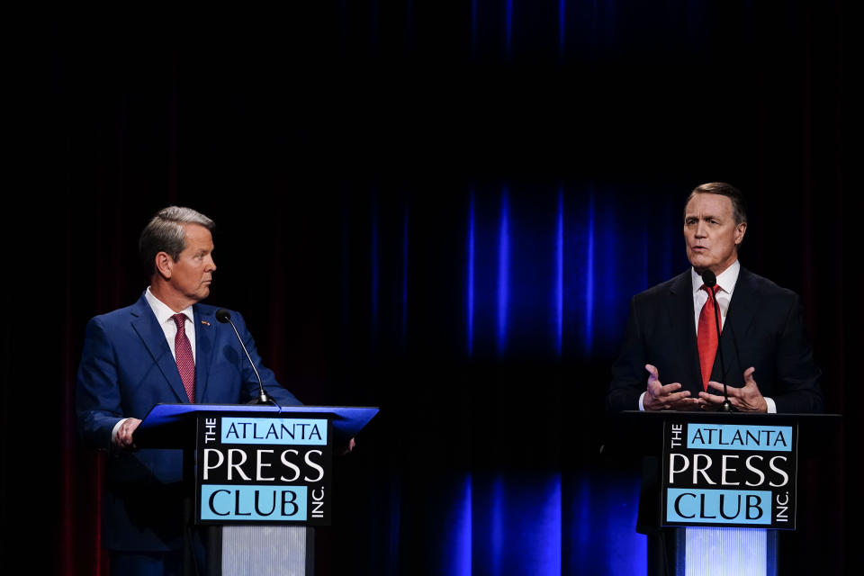 Former Sen. David Perdue, as Gov. Brian Kemp listens, speaks at a podium marked The Atlanta Press. Club Inc.