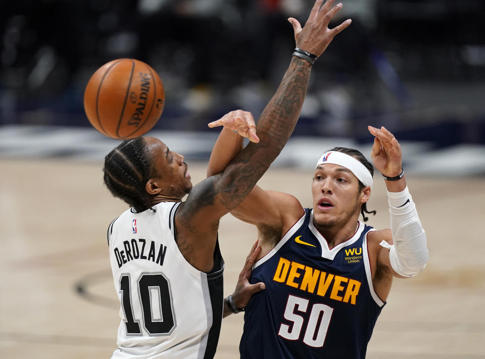 Denver Nuggets forward Aaron Gordon, right, passes the ball as San Antonio Spurs forward DeMar DeRozan defends in the second half of an NBA basketball game Friday, April 9, 2021, in Denver. (AP Photo/David Zalubowski)