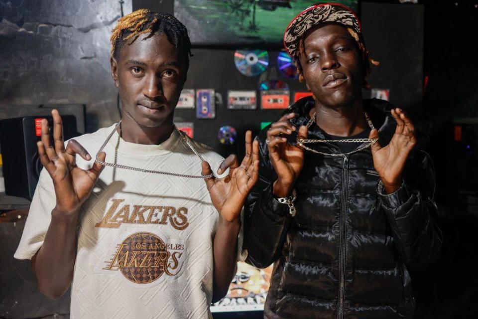 Allan "Manazz" Mojo (L) and Tony "Kantel" Otieno (R) hold their neckchains up.