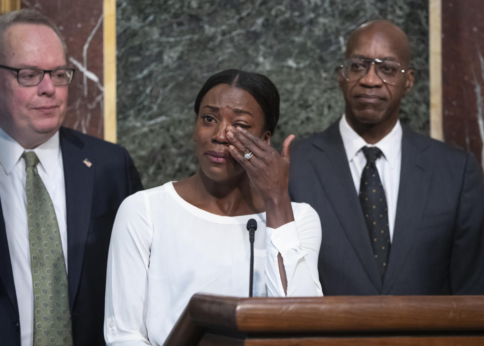 FILE - In this Oct. 31, 2018, file photo, Alysia Montano is flanked by Jim Carroll, deputy director of the Office of National Drug Control Policy, left, and Edwin Moses, chairman of the U.S. Anti-Doping Agency, as she wipes away tears as she recounts her experience finishing behind two Russian runners using performance-enhancing drugs, during a White House event aimed at reforming the World Anti-Doping Agency, in Washington. On Monday, Sept. 30, 2019, Montano walked off the track at the World Championships in Doha, Qatar, with a pair of bronze medals that were placed around her neck several years too late. The U.S. 800-meter runner who has stood up on behalf of every athlete who has ever kept off the medals stand by a doper finally got the third-place prizes she was robbed of at two straight worlds, back in 2011 and 2013. (AP Photo/J. Scott Applewhite, File)