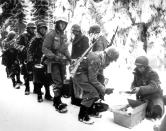 FILE - In this Jan. 13, 1945 file photo, and provided by the U.S. Army, American soldiers of the 347th U.S. Infantry wear heavy winter gear as they receive rations in La Roche, Belgium.It was 75 years ago that Hitler launched his last desperate attack to turn the tide for Germany in World War II. It was 75 years ago that Hitler launched his last desperate attack to turn the tide for Germany in World War II. At first, German forces drove so deep through the front line in Belgium and Luxembourg that the month-long fighting came to be known as The Battle of the Bulge. When the Germans asked one American commander to surrender, the famous reply came: “Nuts!" By Christmas, American troops had turned the tables on the Germans. Veterans are heading and on Monday, Dec. 16, 2019 when they will mix with royalty and dignitaries to mark perhaps the greatest battle in U.S. military history. (U.S. Army, via AP, File)