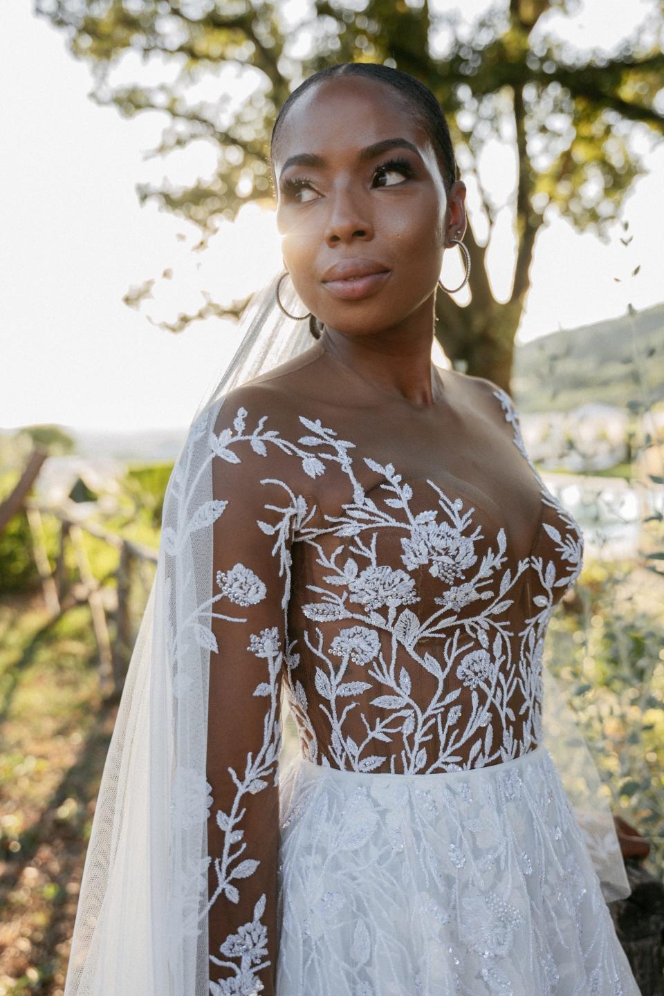 A bride poses in her wedding dress in front of a tree.