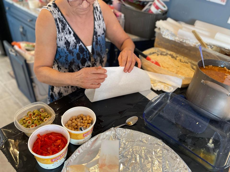 Ashley Fontones' step grandmother Maria demonstrates how to fold pastele paper filled with masa and other toppings.