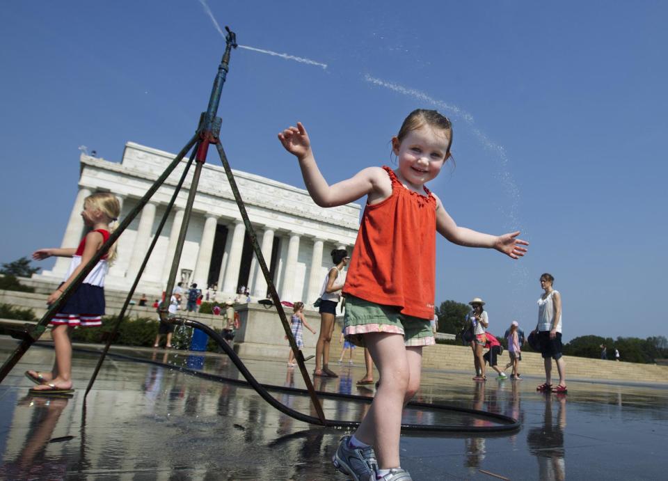 Sophie, 3, from Connecticut, frolics with a water sprinkler set up at the National Mall near the Lincoln Memorial, rear, in Washington Saturday, July 7, 2012. The heat gripping much of the country is set to peak Saturday in many places, including some Northeast cities, where temperatures close to or surpassing 100 degrees are expected. (AP Photo/Manuel Balce Ceneta)