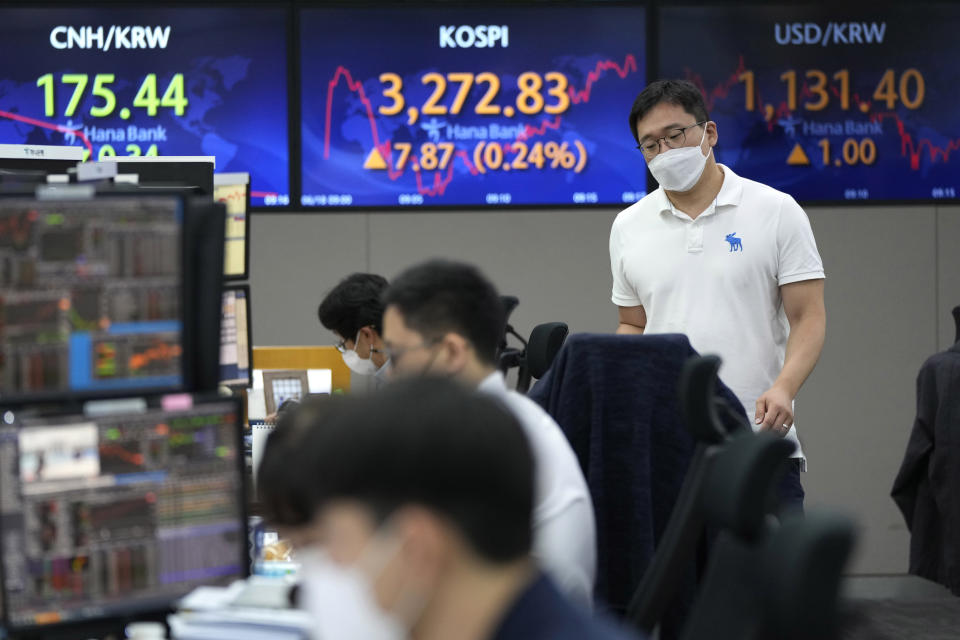 A currency trader passes by screens showing the Korea Composite Stock Price Index (KOSPI), center, and the foreign exchange rate between U.S. dollar and South Korean won, right, at the foreign exchange dealing room of the KEB Hana Bank headquarters in Seoul, South Korea, Friday, June 18, 2021. Asian shares mostly rose Friday, as investors digested the latest message from the U.S. Federal Reserve on raising short-term interest rates by late 2023. (AP Photo/Ahn Young-joon)