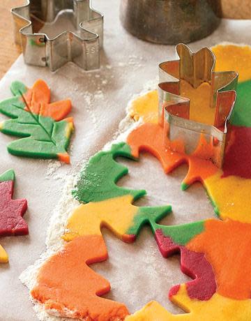 multicolored cookie dough being cut into leaf shapes