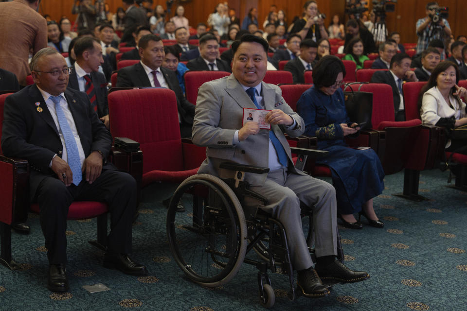 Newly elected opposition Democratic Party lawmaker J. Bayasgalan holds up his Parliamentary membership cards during a ceremony at the Mongolian Government Palace in Ulaanbaatar, Mongolia, Monday, July 1, 2024. (AP Photo/Ng Han Guan)