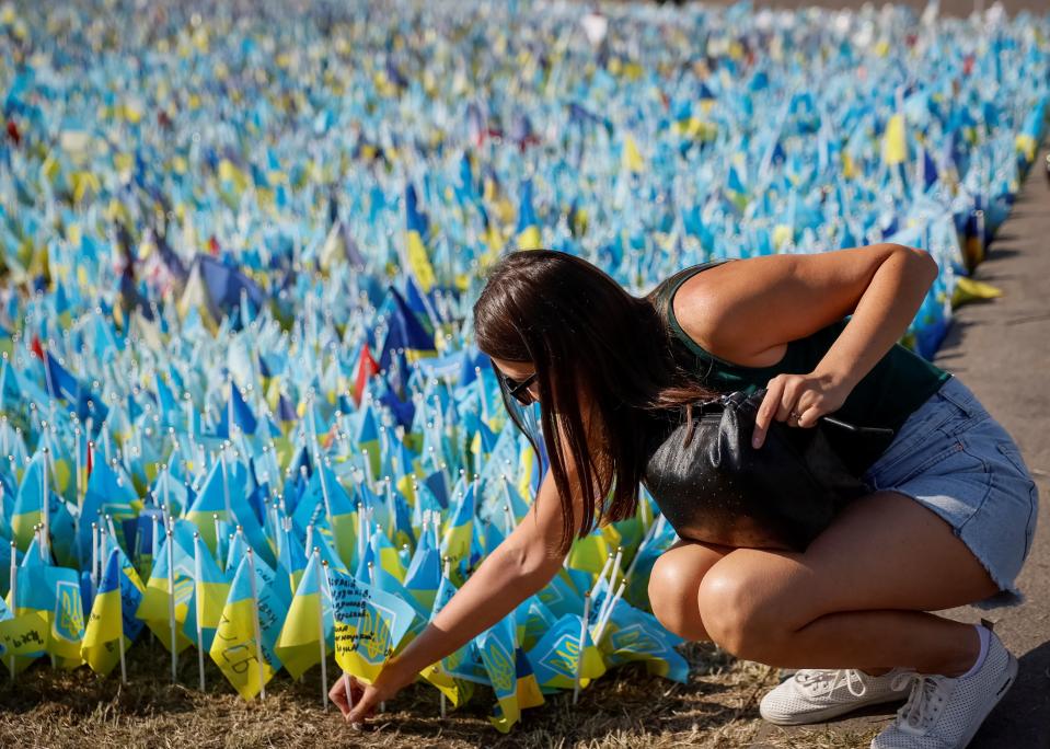 A relative places a Ukrainian flag with the name of a fallen service member at a makeshift memorial place at the Independence Square (REUTERS)