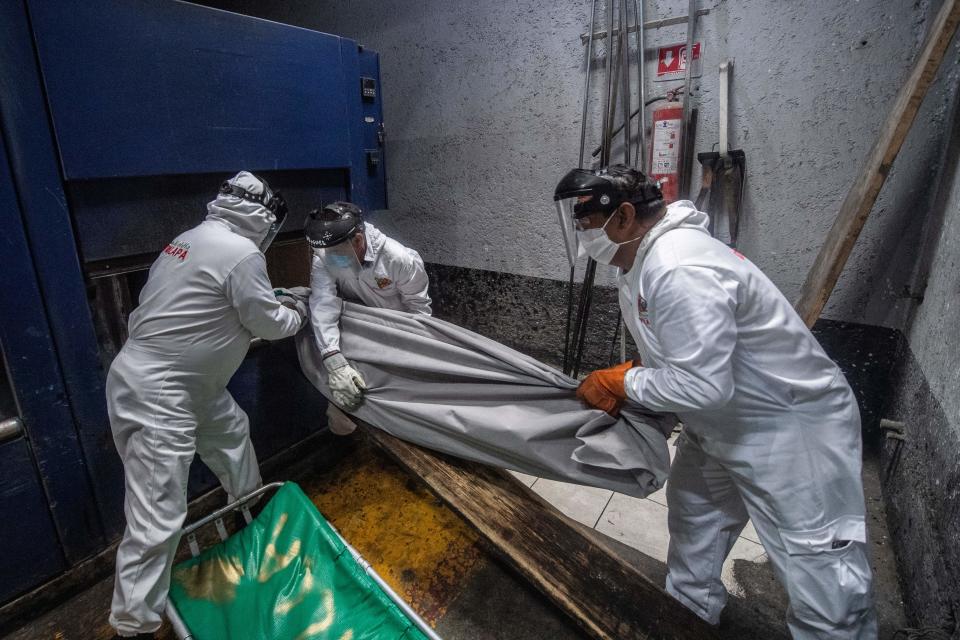 Los empleados del crematorio introducen en el horno el cuerpo de un fallecido por Covid-19 que va a ser incinerado. (Photo by PEDRO PARDO/AFP via Getty Images)