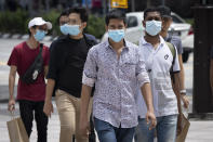 Pedestrians wearing face mask cross a junction in downtown Kuala Lumpur, Malaysia, on Sunday, June 7, 2020. Malaysian government has lifted the conditional movement order (CMCO) and replaced it with a recovery movement control order effective June 10 until Aug. 31. (AP Photo/Vincent Thian)