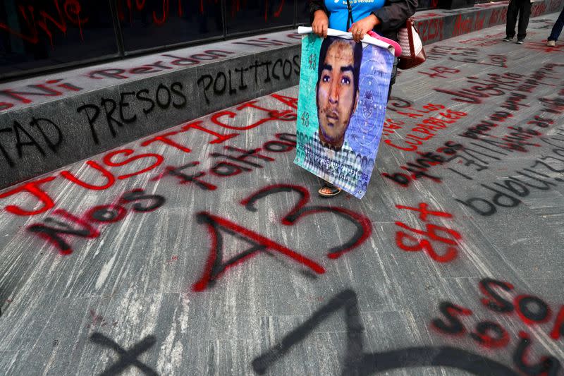 FILE PHOTO: A relative of a missing student holds a poster with his image during a protest outside the Attorney General's office, in Mexico City