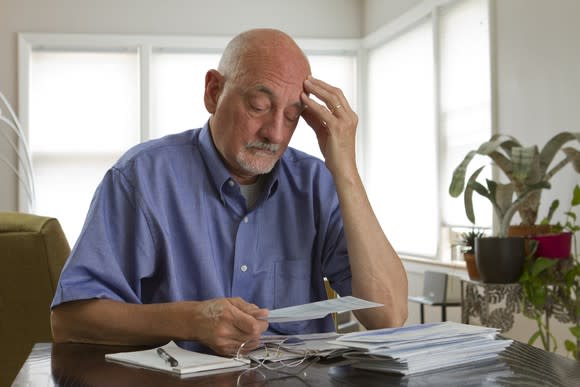 Senior man looking depressed at a stack of papers