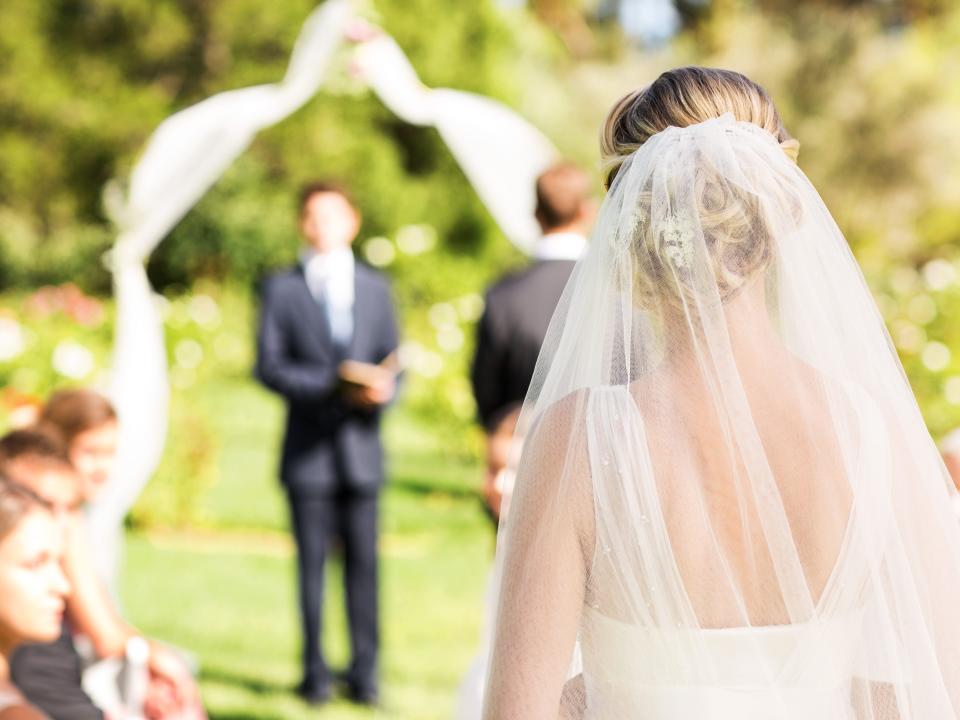 A bride walks down the aisle of an outdoor wedding