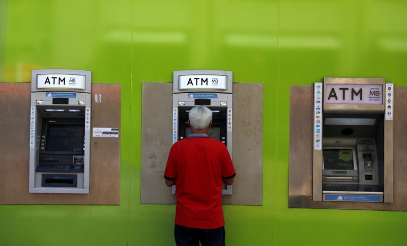 A man uses an ATM at a Novo Banco branch in downtown Lisbon