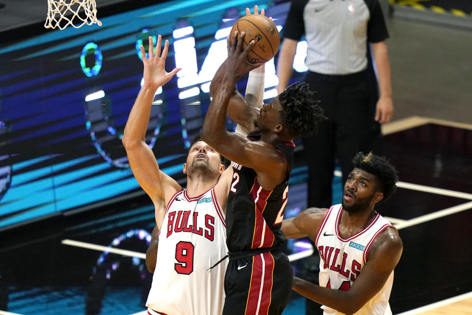 Miami Heat forward Jimmy Butler, center, is fouled by Chicago Bulls center Nikola Vucevic (9) during the second half of an NBA basketball game, Monday, April 26, 2021, in Miami. At right is Chicago Bulls forward Patrick Williams. (AP Photo/Lynne Sladky)