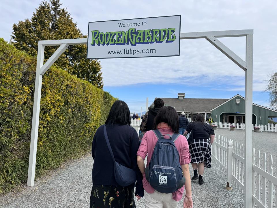 People walking under a sign that reads "Welcome to RoozenGaarde www.tulips.com."