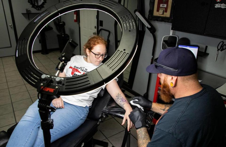 Jonathan Pope, right, cleans up the tattoo stencil while preparing to tattoo Sarah Mente Tuesday at From The Ashes Tattoo Studio in Gastonia.