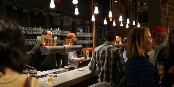 A crowd of people in a bar with two bartenders behind the taps