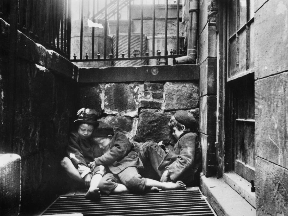 Three young boys huddle together for warmth in New York in 1895.