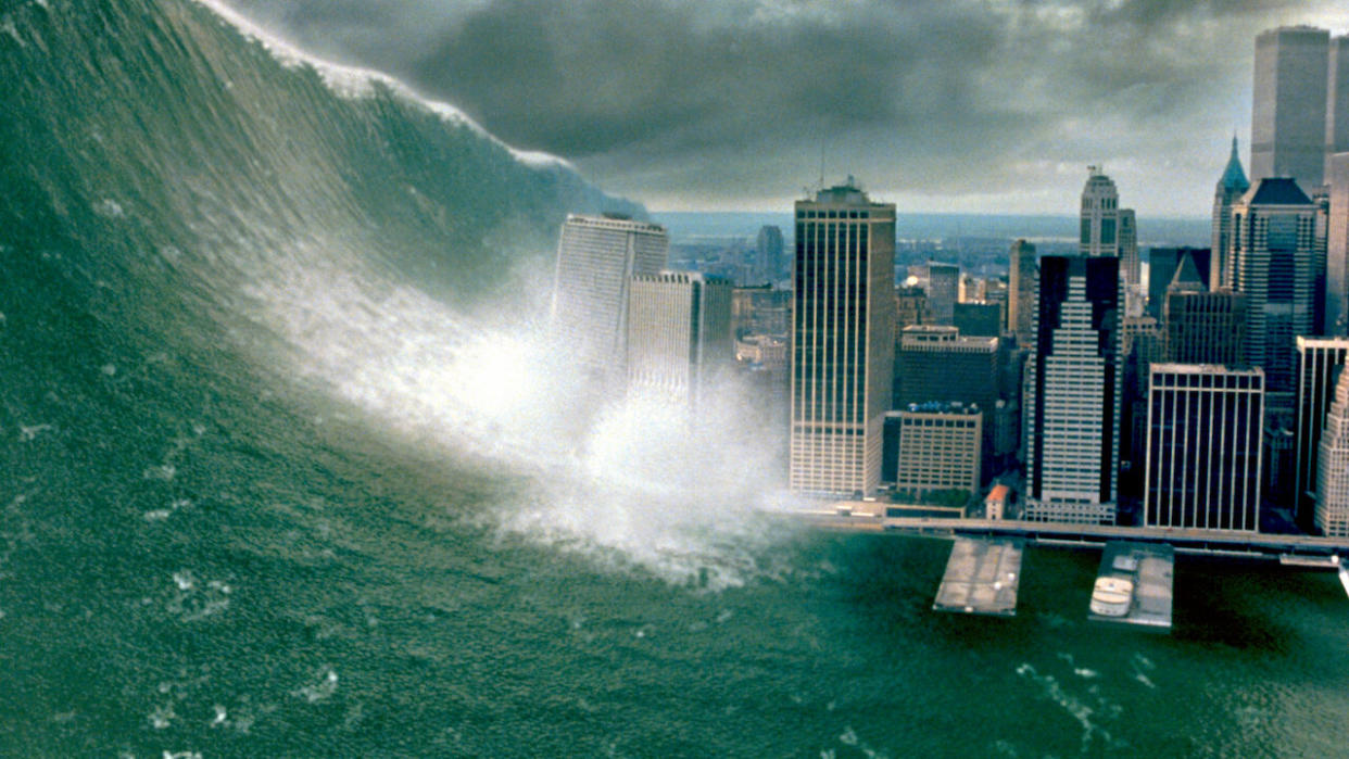  Still from the movie Deep Impact, showing a huge wave crashing into a city with tall buildings  