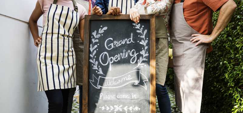 Workers standing by a chalkboard sign reading Grand Opening