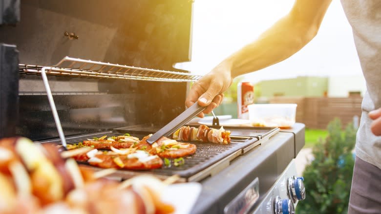 Person grilling meat and vegetables