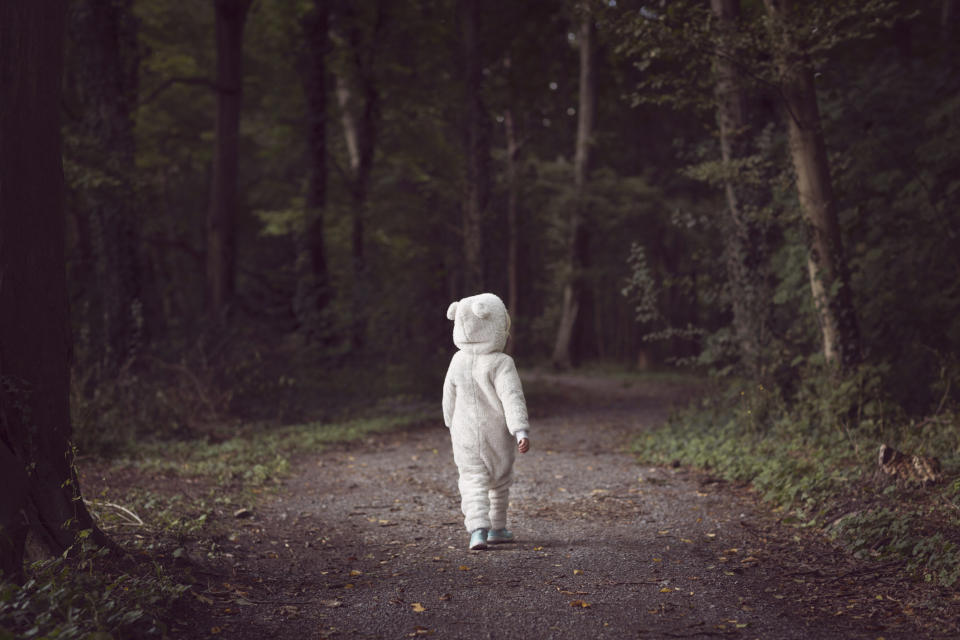 A child in a costume walking in the woods