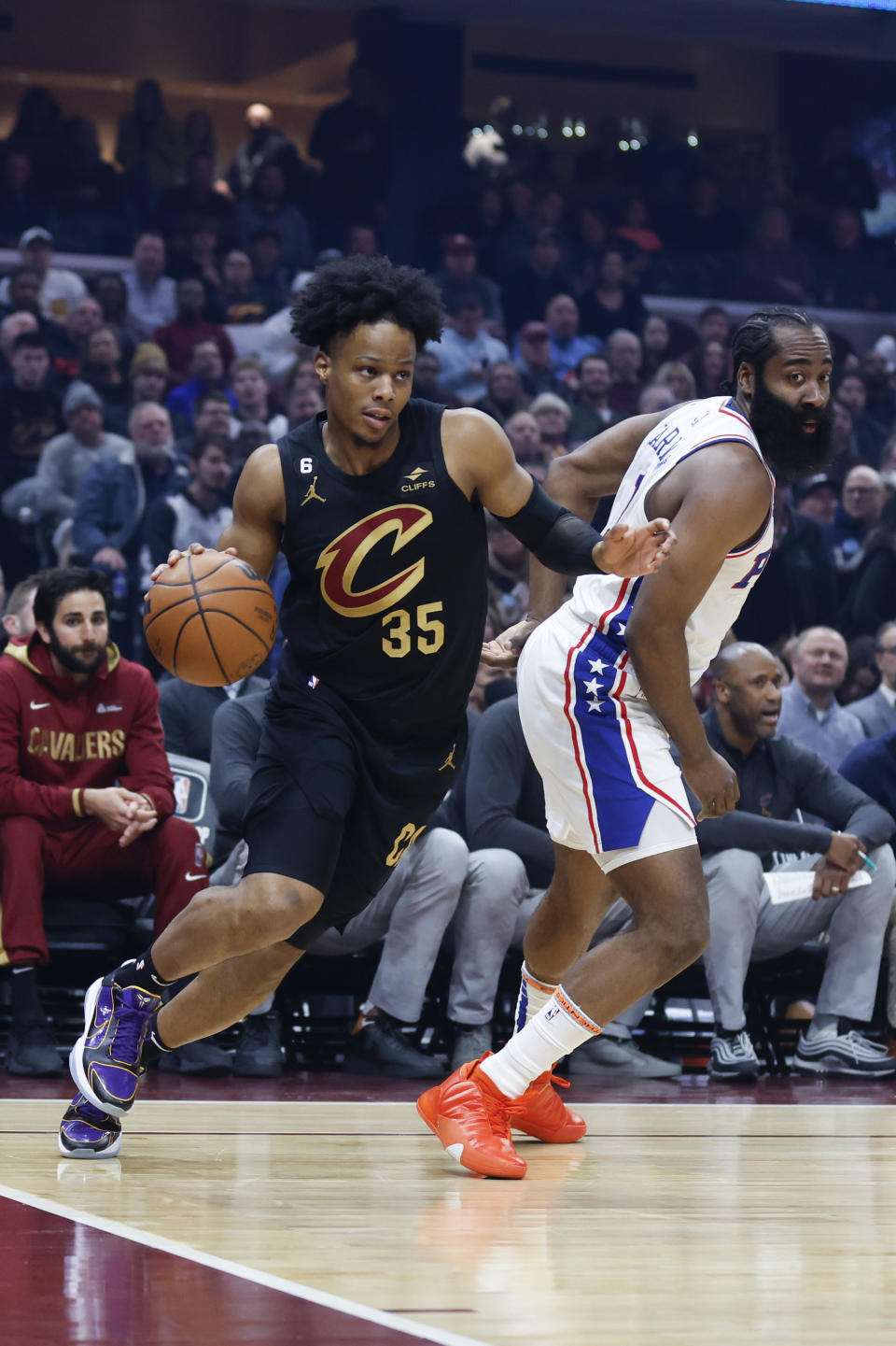 Cleveland Cavaliers forward Isaac Okoro (35) drives against Philadelphia 76ers guard James Harden (1) during the first half of an NBA basketball game, Wednesday, March 15, 2023, in Cleveland. (AP Photo/Ron Schwane)