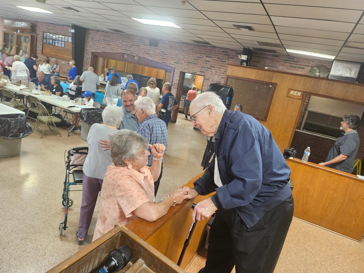 The Rev. Frederic J. Brunet meets with Phyllis Robichaux at a school reunion in Chauvin, April 27. The community gathered to celebrate its past and take photos of those who attended or taught at four closed schools.