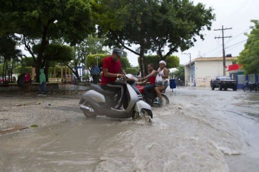 Local residents stay under the rain in Enriquillo, southwestern Dominican Republic. Tropical Storm Isaac gained strength as it roared towards the Domincan Republic and Haiti, where it was to make landfall later in the day, threatening survivors of a devastating 2010 earthquake