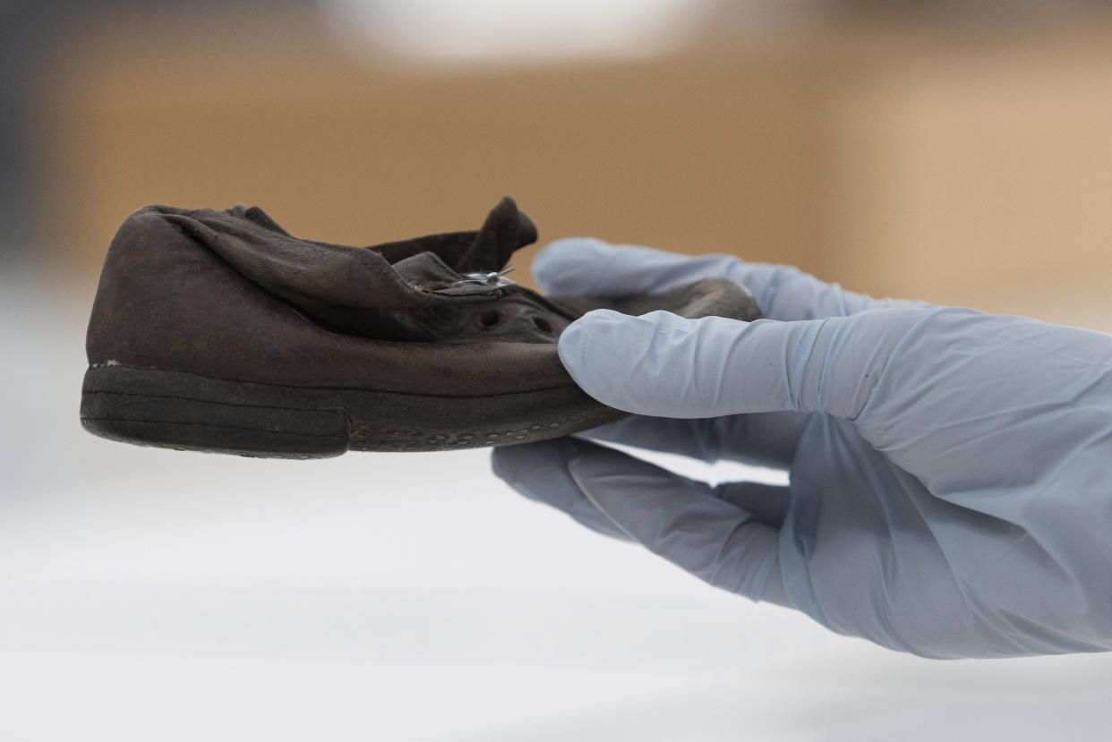 A worker holds a shoe that belonged to a child victim of the former Nazi German death camp Auschwitz-Birkenau at the conservation laboratory on the grounds of the camp in Oswiecim, Poland, Wednesday, May 10, 2023. Museum workers describe the children's shoes as one of the most emotional testaments of the crimes carried out at Auschwitz, where Nazi German forces murdered 1.1 million people during World War II. (AP Photo/Michal Dyjuk)