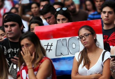 A protester holds a sign in the colours of Paraguay's national flag that reads NO during a students' rally against a proposed amendment that would allow Paraguay's president to stand for re-election in Asuncion, Paraguay, April 2, 2017. REUTERS/Marcos Brindicci