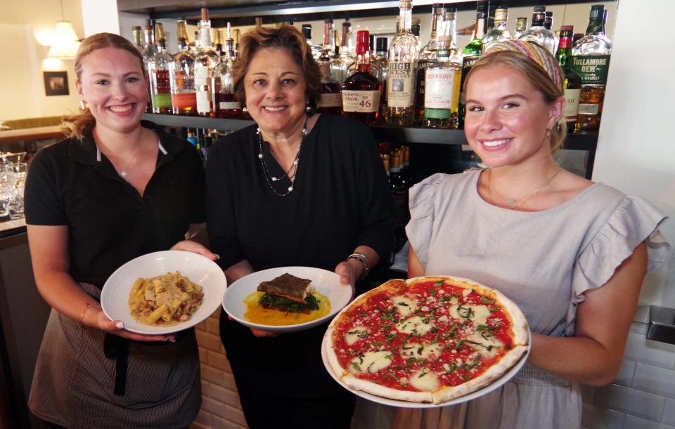 From left, Corfinio of Easton staff show off some of the restaurants dishes, Reese Blass with the norcina rigatoni, manager Lucia Marinai with the pan roasted cod with spinach, and Georgia Costello, holding the pizza Margherita, on Thursday, July 13, 2023.
