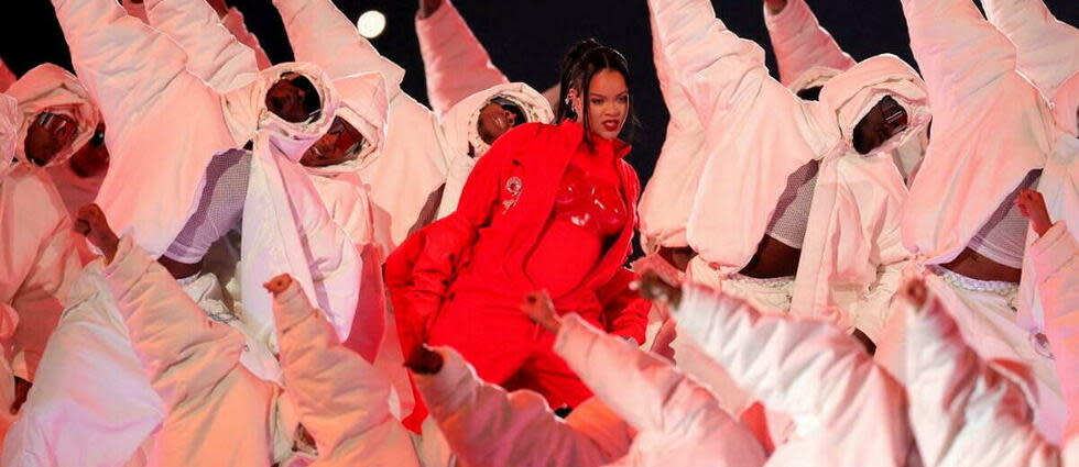 Vêtue d'une combinaison rouge et d'un manteau assorti, Rihanna évoluait au milieu de plusieurs centaines de danseurs, tous habillés en combinaison blanche intégrale, certains sur des plateformes surélevées, d'autres sur le terrain même.  - Credit:CARMEN MANDATO / GETTY IMAGES NORTH AMERICA / Getty Images via AFP