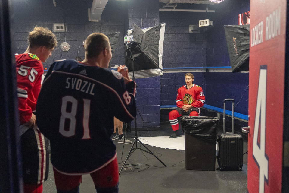 Chicago Blackhawks' Connor Bedard, right, the number one overall draft pick, gets his portrait taken as Chicago Blackhawks' Kevin Korchinski, left, and Columbus Blue Jackets' Stanislav Svozil encourage him, during the NHL Players Association rookie showcase, Tuesday, Sept. 5, 2023 in Arlington, Va. (AP Photo/Alex Brandon)