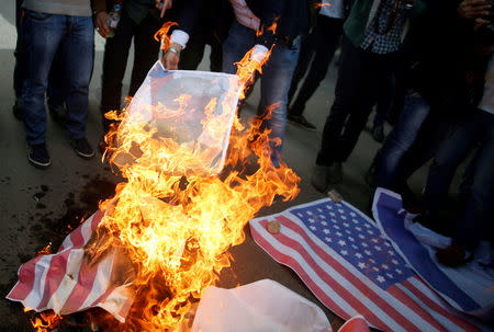 Palestinian protesters burn a poster depicting U.S. President Donald Trump and a representation of a U.S. flag during a protest against Trump's decision to recognize Jerusalem as the capital of Israel, in Gaza City December 7, 2017. REUTERS/Mohammed Salem