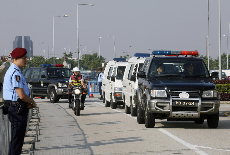 Former Transport and Public Works Secretary Ao Man-long, carried by one of the white vans, arrives at a packed court in a convoy of police and prison vehicles in Macau, Monday, Nov. 5, 2007. A senior Macau official went on trial Monday charged with allegedly amassing US$100 million (euro69 million) in kickbacks during his seven years in office in the tiny gambling enclave, which has struggled to shake off its links to crime. (AP Photo)