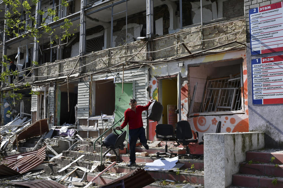 A man carries chairs out of an office on a ground floor of an apartment building destroyed by night shelling in Kramatorsk, Ukraine, Thursday, May 5, 2022. (AP Photo/Andriy Andriyenko)