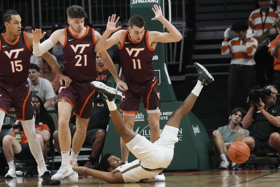 Miami guard Harlond Beverly (5) stumbles with the ball as Virginia Tech forwards John Camden (11) and Grant Basile (21) show their hands up during the first half of an NCAA college basketball game, Tuesday, Jan. 31, 2023, in Coral Gables, Fla. (AP Photo/Marta Lavandier)