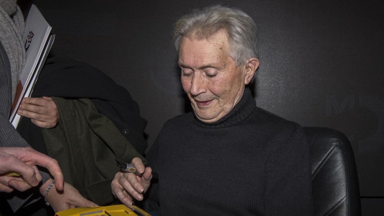 portrait of marcello gandini while he autographs a model car