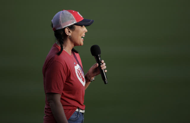 Kristi Moore speaks on the field before a baseball game between the Miami Marlins and the Atlanta Braves on Friday, April 22, 2022, in Atlanta. Moore was punched in the face less than two weeks ago by a parent who did not agree with her call on a play at second base at a girls' softball game in Mississippi. Major League Baseball umpires Lance Barksdale and Ted Barrett were outraged when they heard of the assault of Moore. They wanted to show their support, so they invited her to the game Friday which they are calling. (AP Photo/Ben Margot)