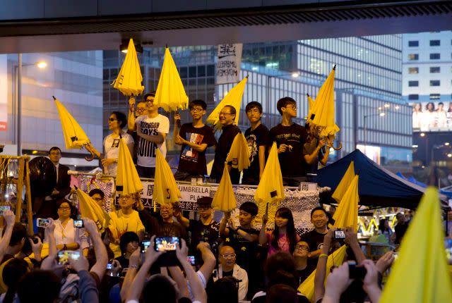 Protesters, including Joshua Wong, carry yellow umbrellas at an Umbrella Movement demonstration in Hong Kong in October 2014.